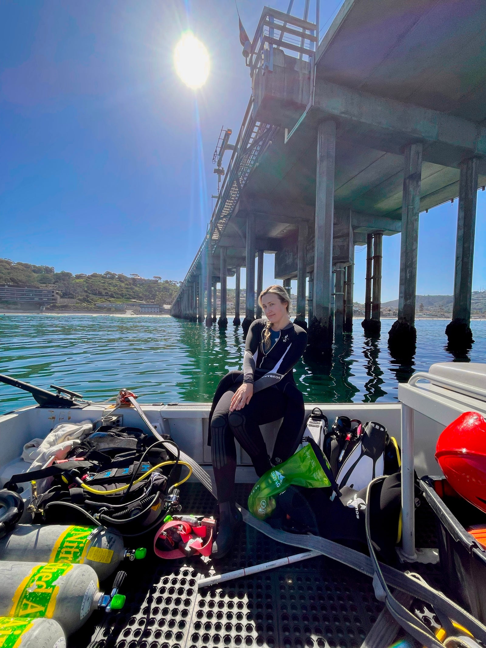 Caelie with diving equipment beside the pier in La Jolla